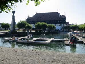 A riverside area with boats docked, a statue, and a large building with a steep roof. - Atelier Probst Apartment K0, 40 sqm with Wi-Fi (Konstanz)