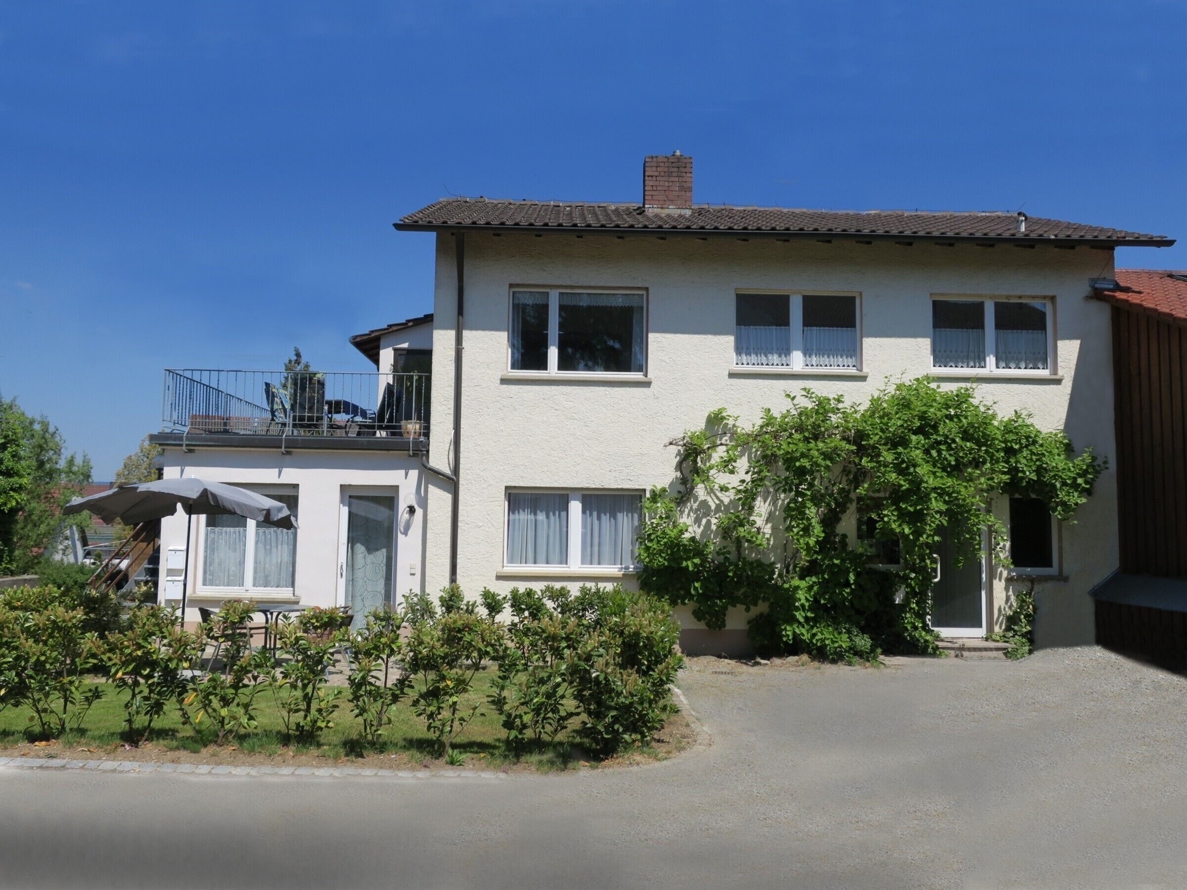 Een twee verdiepingen tellend huis met een balkon, een overdekte patio en een oprit.