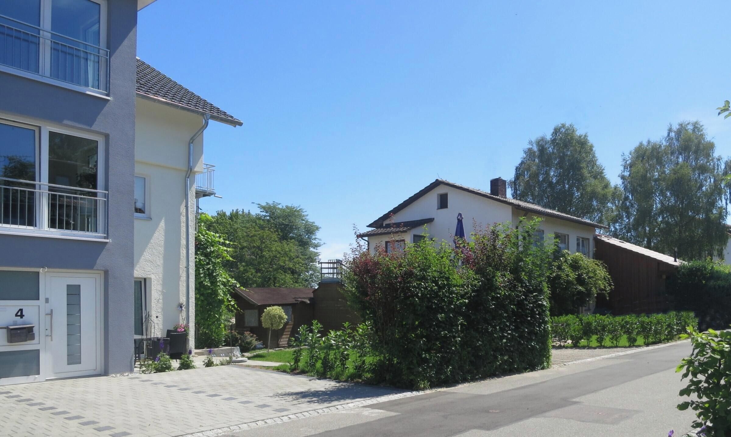 Ein Wohngebiet mit einem zweistöckigen Haus, einer gepflasterten Auffahrt und blauem Himmel.