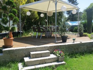 A covered outdoor patio with a table and chairs, surrounded by potted plants and a stone wall. - Apartment 'D3, 40qm' with Private Garden and Wi-Fi (Konstanz)