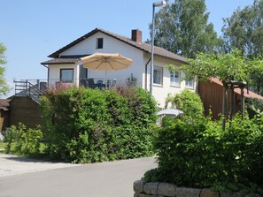 A two-story house with a balcony, a stone wall, and a large umbrella. - Apartment 'D3, 40qm' with Private Garden and Wi-Fi (Konstanz)