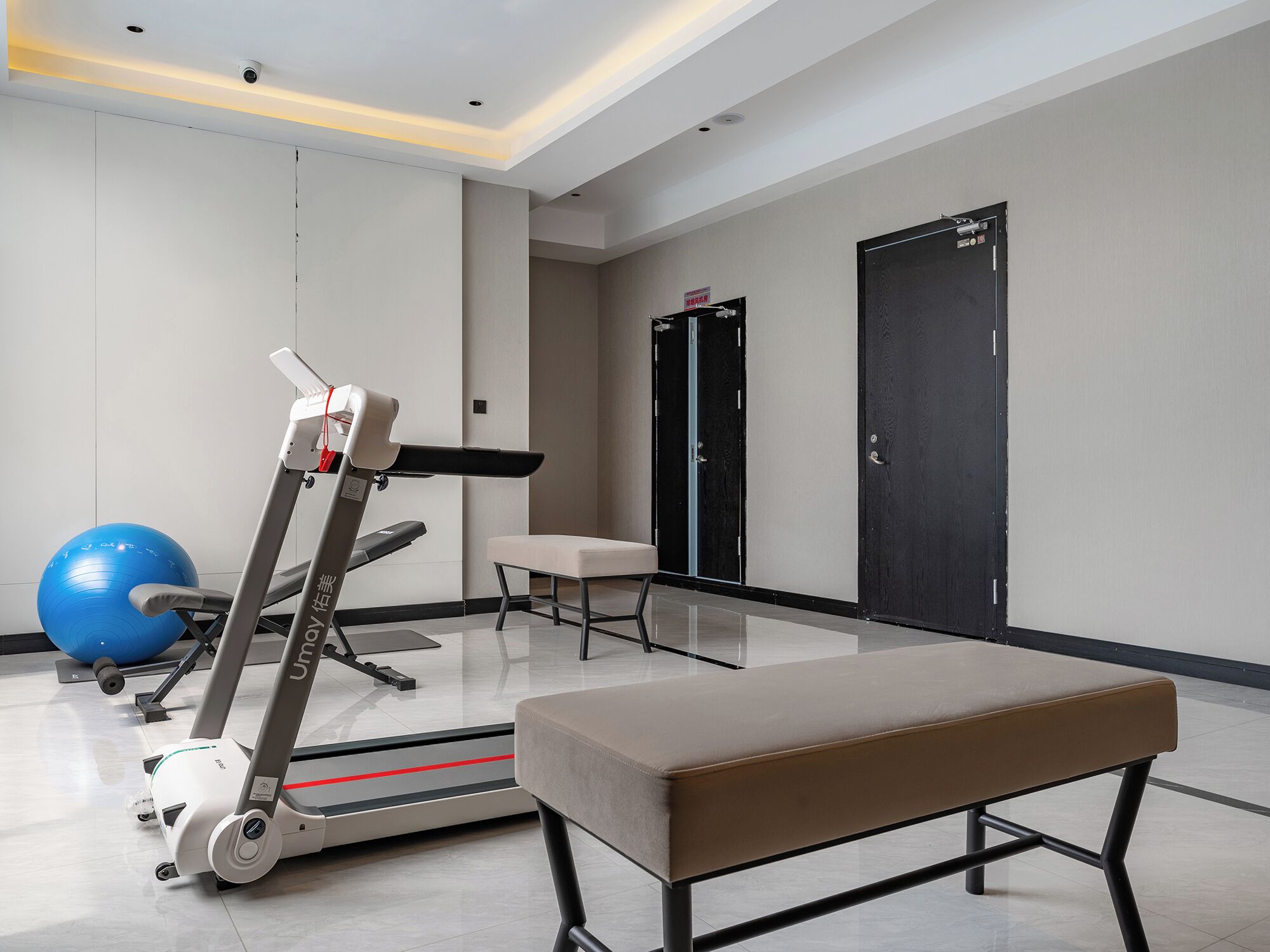 A modern gym with exercise equipment, a bench, and a blue exercise ball.