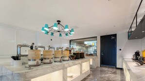 A modern kitchen with a marble countertop, built-in appliances, and a unique teal chandelier. - xana Hotel  (Qionghai)