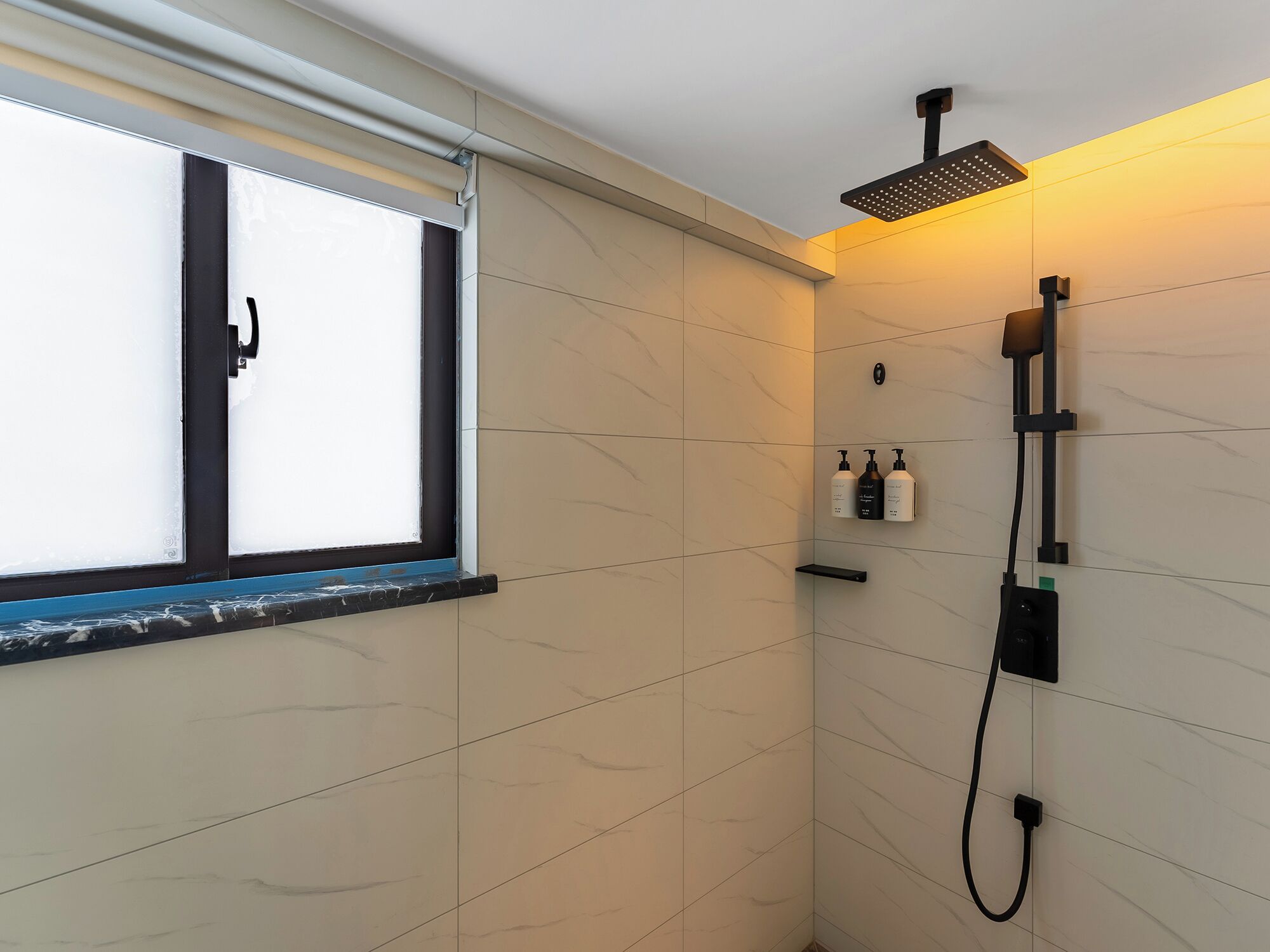 A modern bathroom with a shower, a window, and a shelf with toiletries.