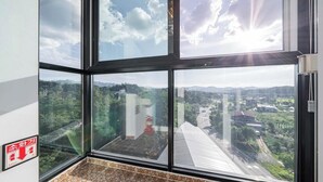 A room with large windows offering a view of a cityscape and greenery. - peach motel (Wonju)