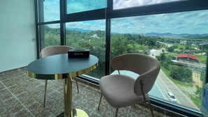 A room with a large window, a table with a box labeled "PEACH HOTEL", and two chairs. - peach motel (Wonju)
