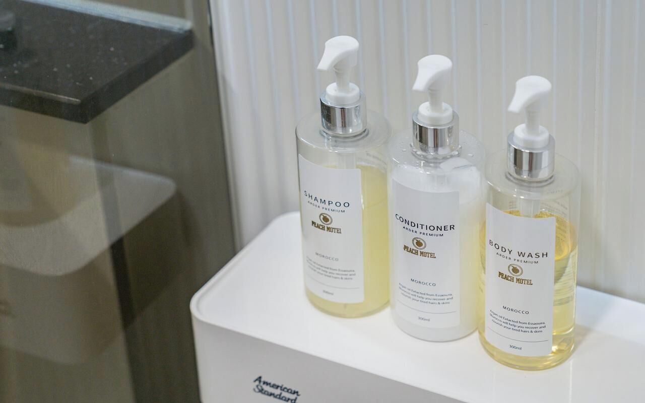 Tres botellas de champú, acondicionador y gel de baño sobre un estante blanco.