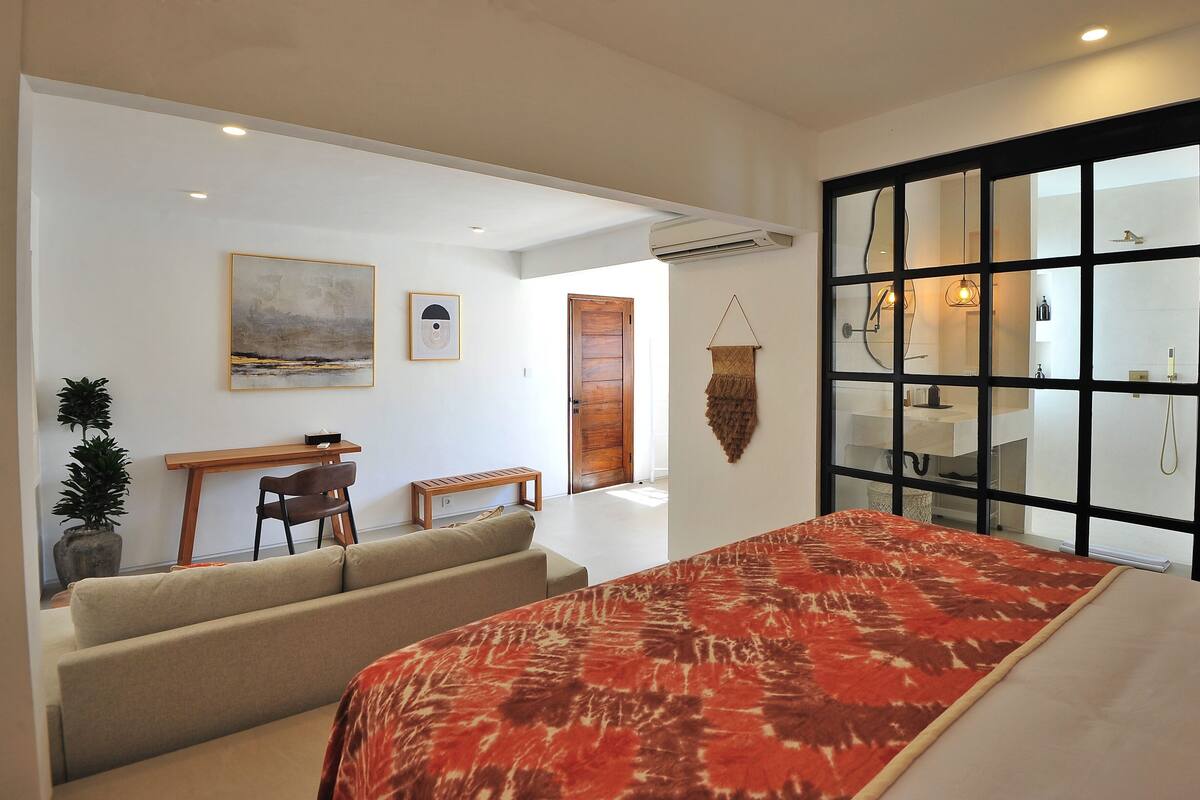 A modern bedroom with a large bed, a desk, and a sofa.