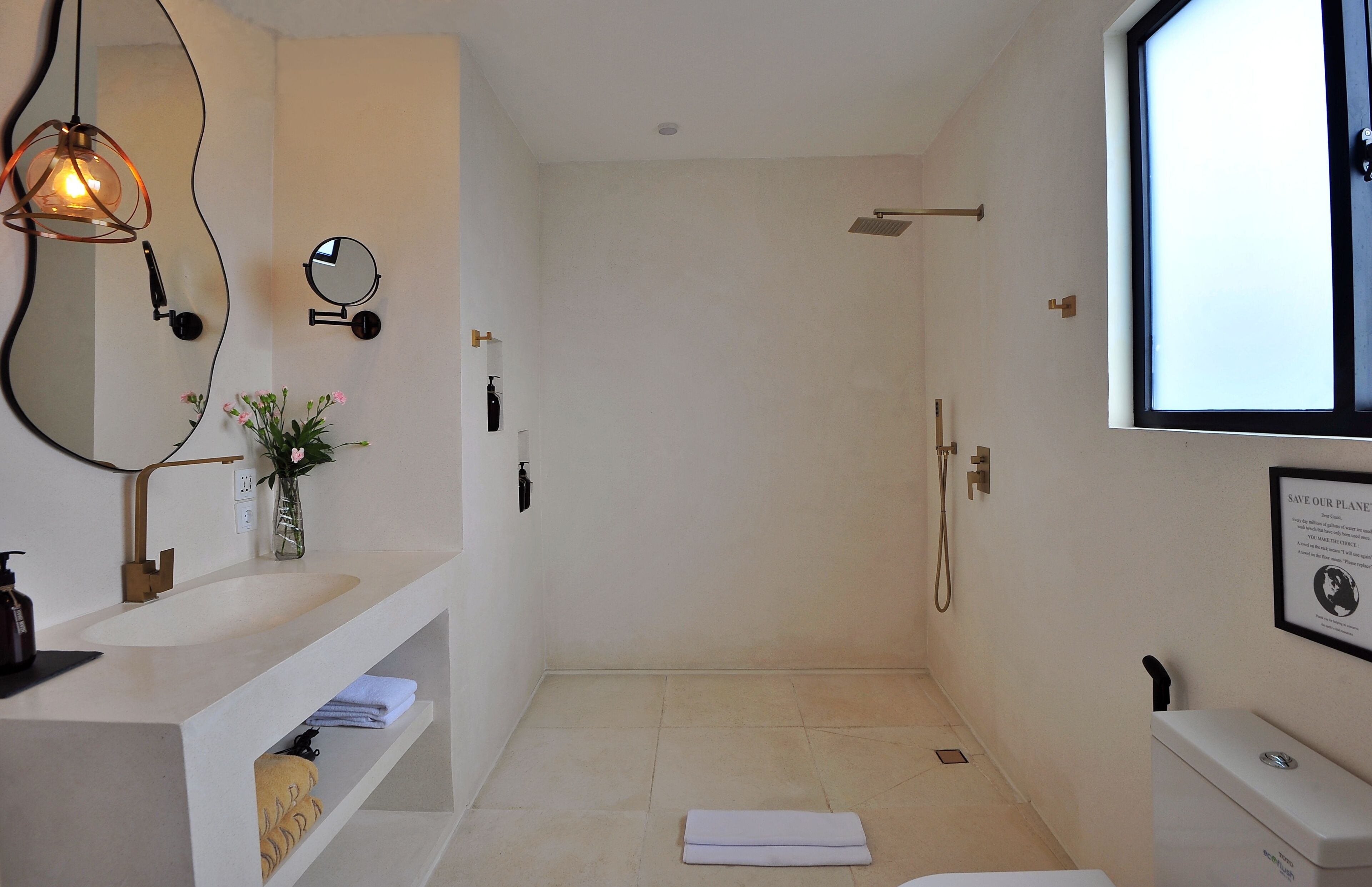 A modern bathroom with a large mirror, a sink, a shower, and a toilet.
