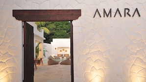 An entrance to a hotel with a stone wall and the name 'AMARA' above it.