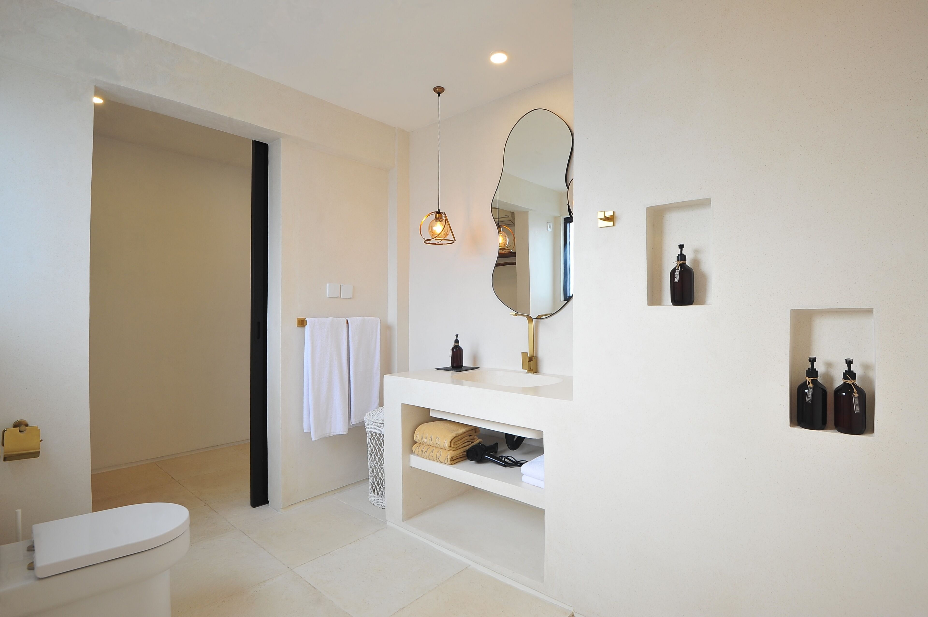 Un baño moderno con inodoro, lavamanos, espejo y toallero.