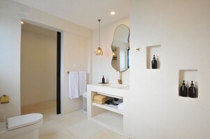 Un baño moderno con inodoro, lavamanos, espejo y toallero.