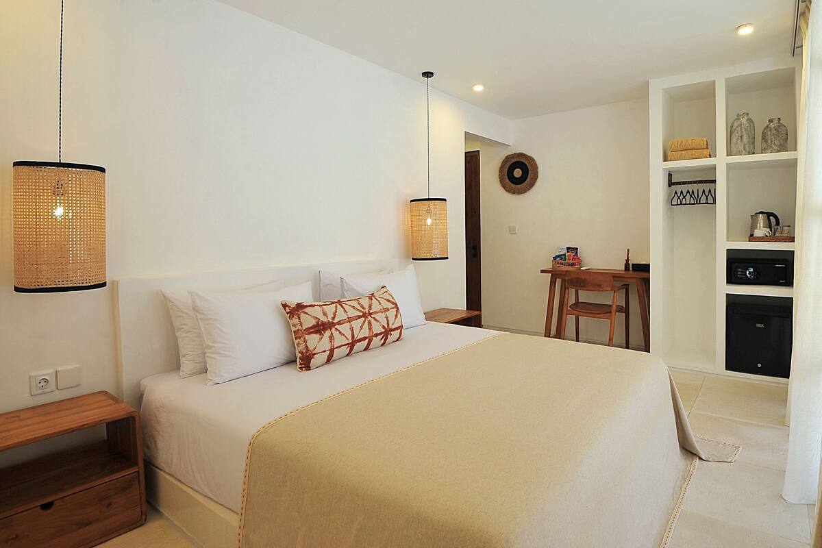 A neatly arranged bedroom with a bed, bedside tables, a desk, and a wardrobe.