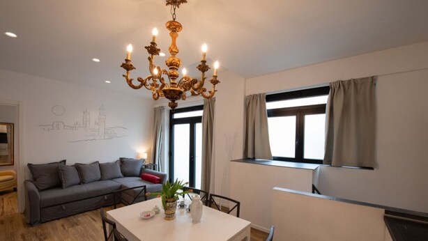 A modern living room with a dining table, sofa, and a chandelier.