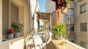 A balcony with a hanging chair, potted plants, and a small table with a bowl. - Florentin Stylish Stay by Sea N' Rent (Tel Aviv)