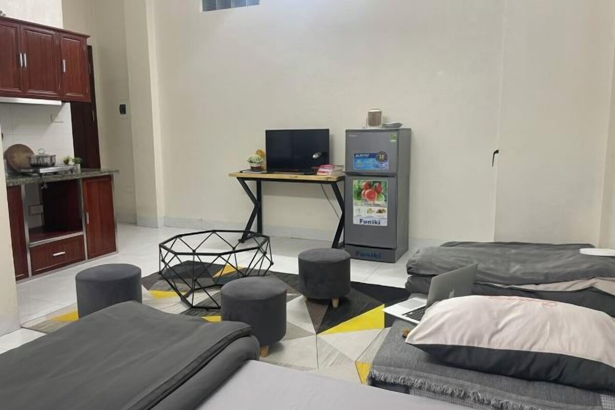 A modern room with a bed, a desk, a refrigerator, and a cabinet.