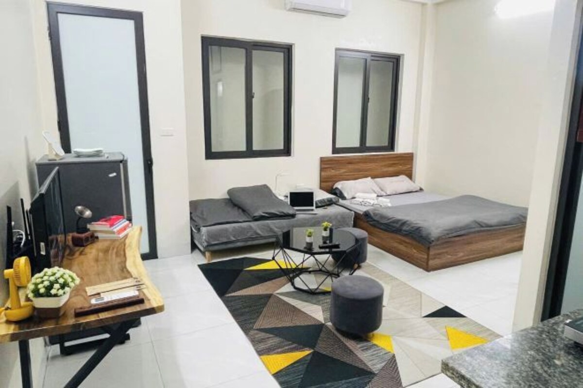 A compact bedroom with a bed, a desk, and a sofa.