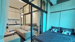 A modern bedroom with a large bed, a sofa, and a small kitchenette. - The Little'N Homestay (Hanoi)