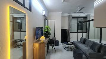 A modern living room with a sofa, a coffee table, a TV, and a plant.