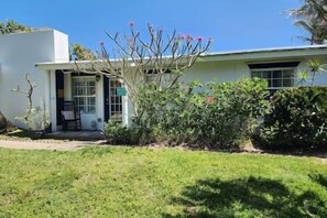 Simple, single-story home with a clean design, featuring a porch and well-manicured yard.