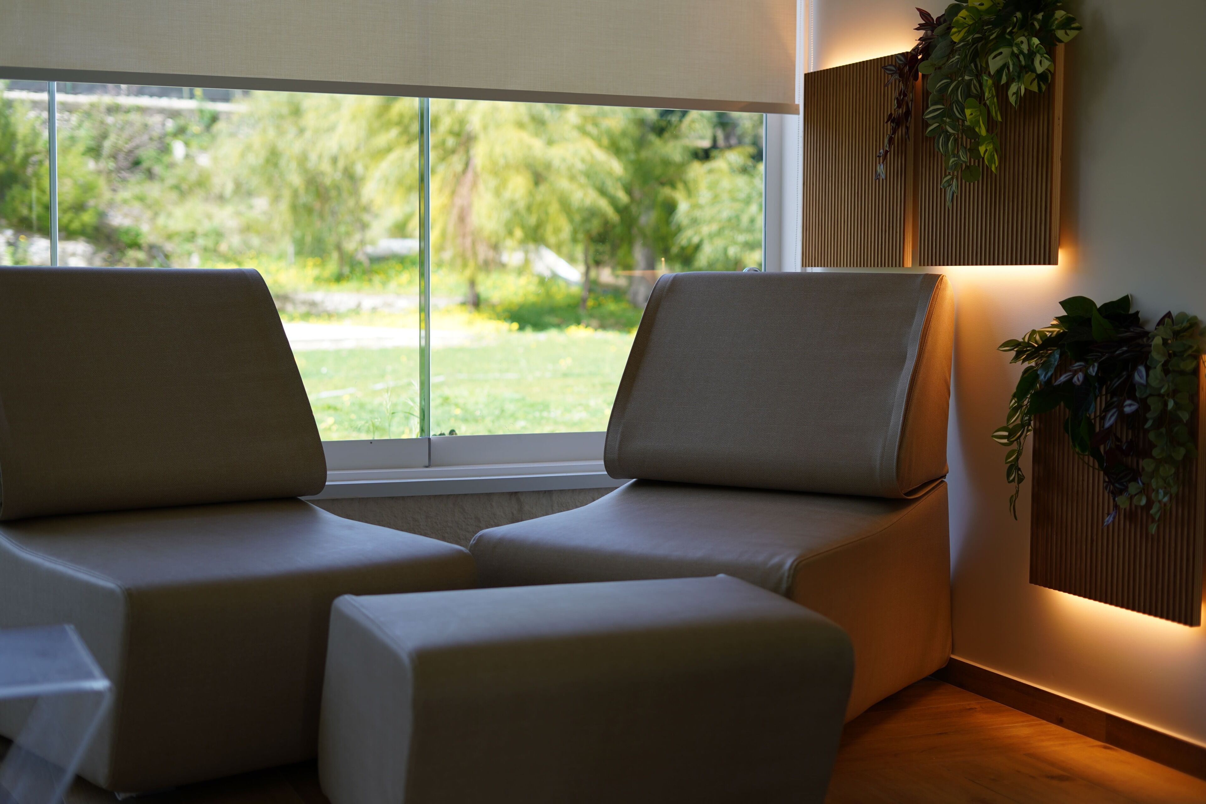 A modern room with a sofa, a small table, and a window with a view of greenery.