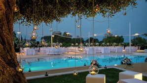 Ein Hochzeitaufbau am Pool mit schwebenden Glaskugeln, weißen Tischen und einem klaren Schwimmbecken.