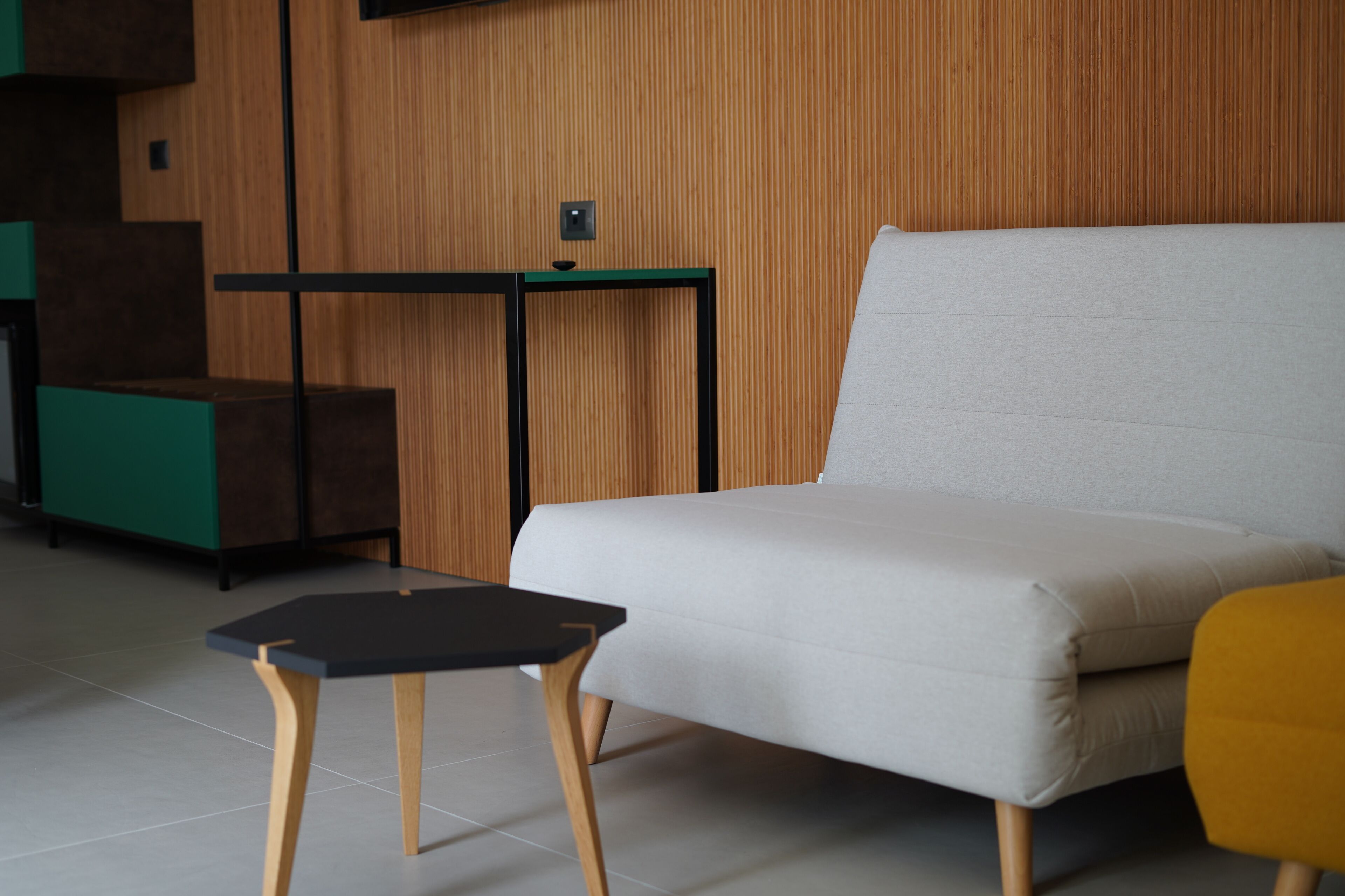 Un salon moderne avec un canapé, une petite table et un élément décoratif vert qui apporte une touche de couleur.