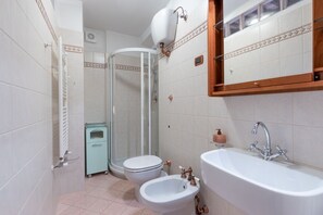Ein Badezimmer mit Dusche, Toilette, Bidet und Waschbecken.
