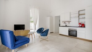 Ein modernes Wohnzimmer mit einem blauen Sofa, einem Fernseher und zwei blauen Sesseln.