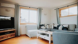 A living room with a TV, sofa, and coffee table. - Spindrift Falmouth, adventurers coastal haven (Break O'Day)
