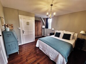 A bedroom with a bed, a dresser, a chandelier, and a door. - MANOIR LE COUTUREAU (Rouffignac-de-Sigoulès)