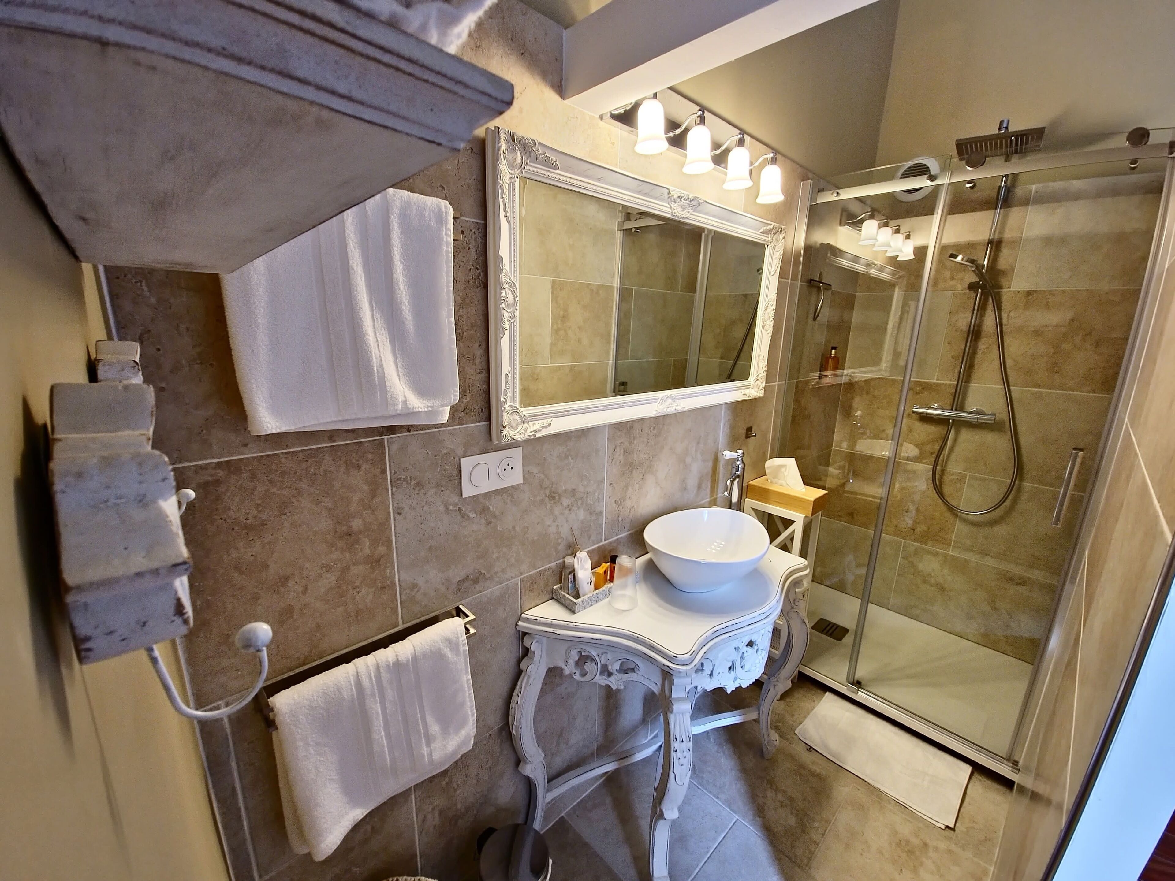 A bathroom with a large mirror, a sink, a shower, and a towel rack.