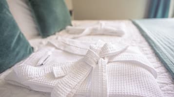Un lit bien fait, avec des serviettes blanches et un oreiller vert.