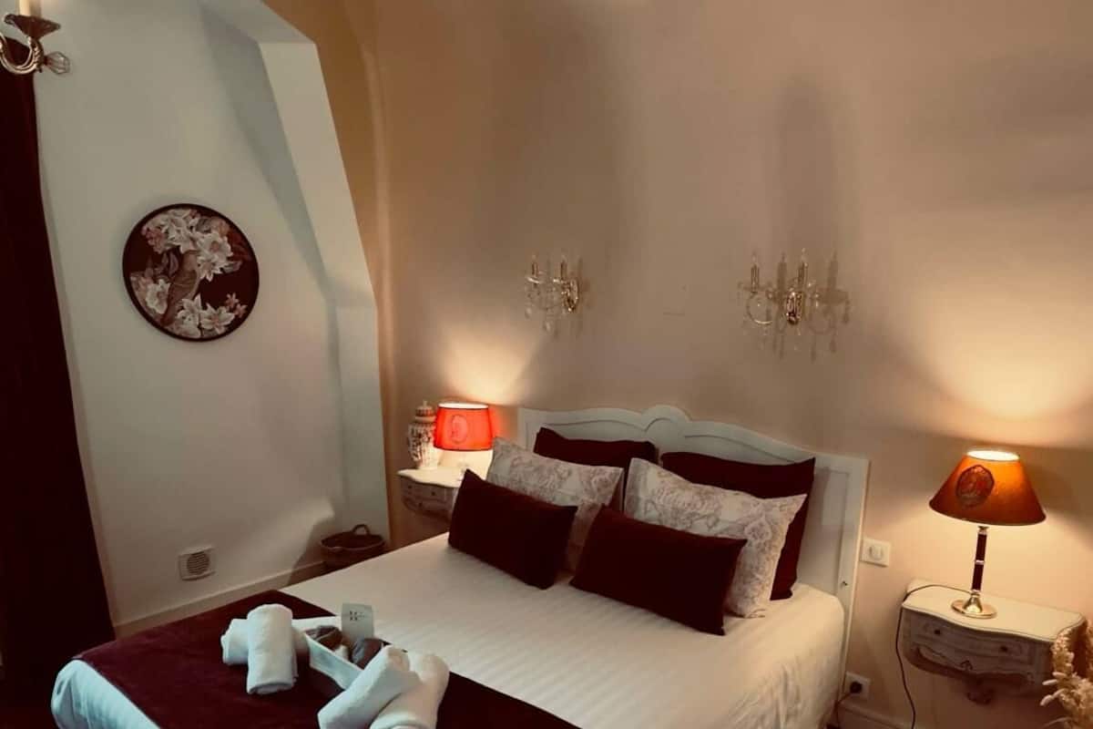 Una camera da letto con un letto grande, due comodini con lampade, una sveglia a parete e un piatto decorativo.