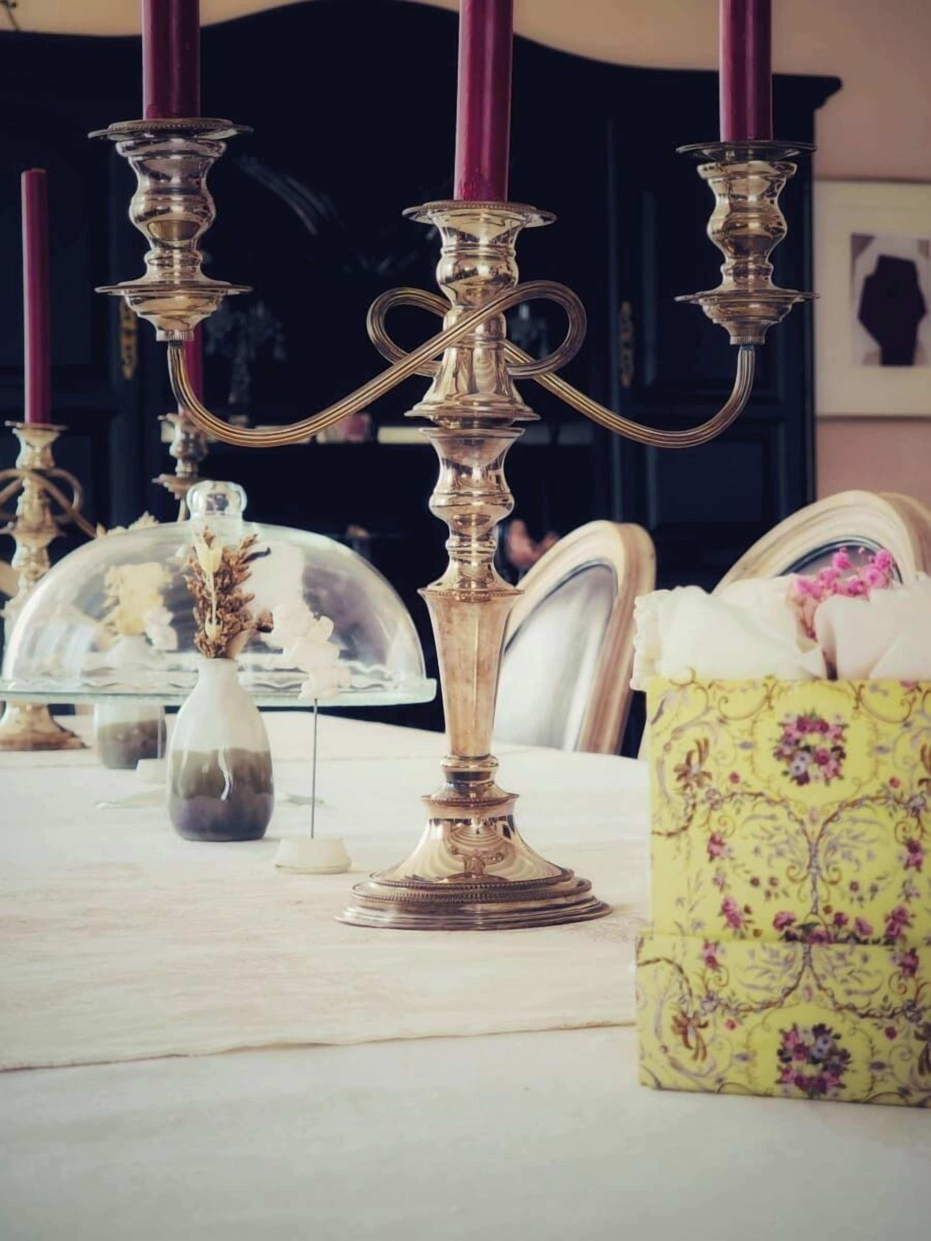 A table with a glass dome centerpiece, a floral-patterned box, and ornate candle holders.