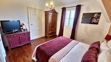 Un dormitorio con cama, televisor en una cómoda, armario y ventana con cortinas.