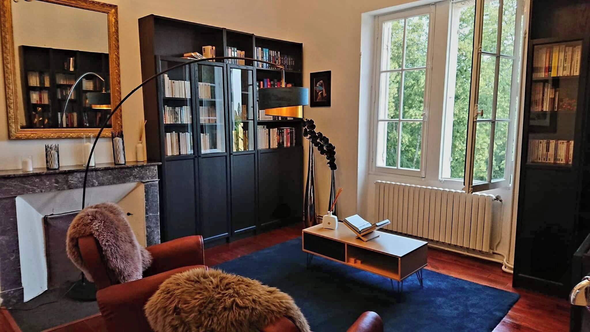 Una sala de estar acogedora con chimenea, estantería y un ventanal grande.