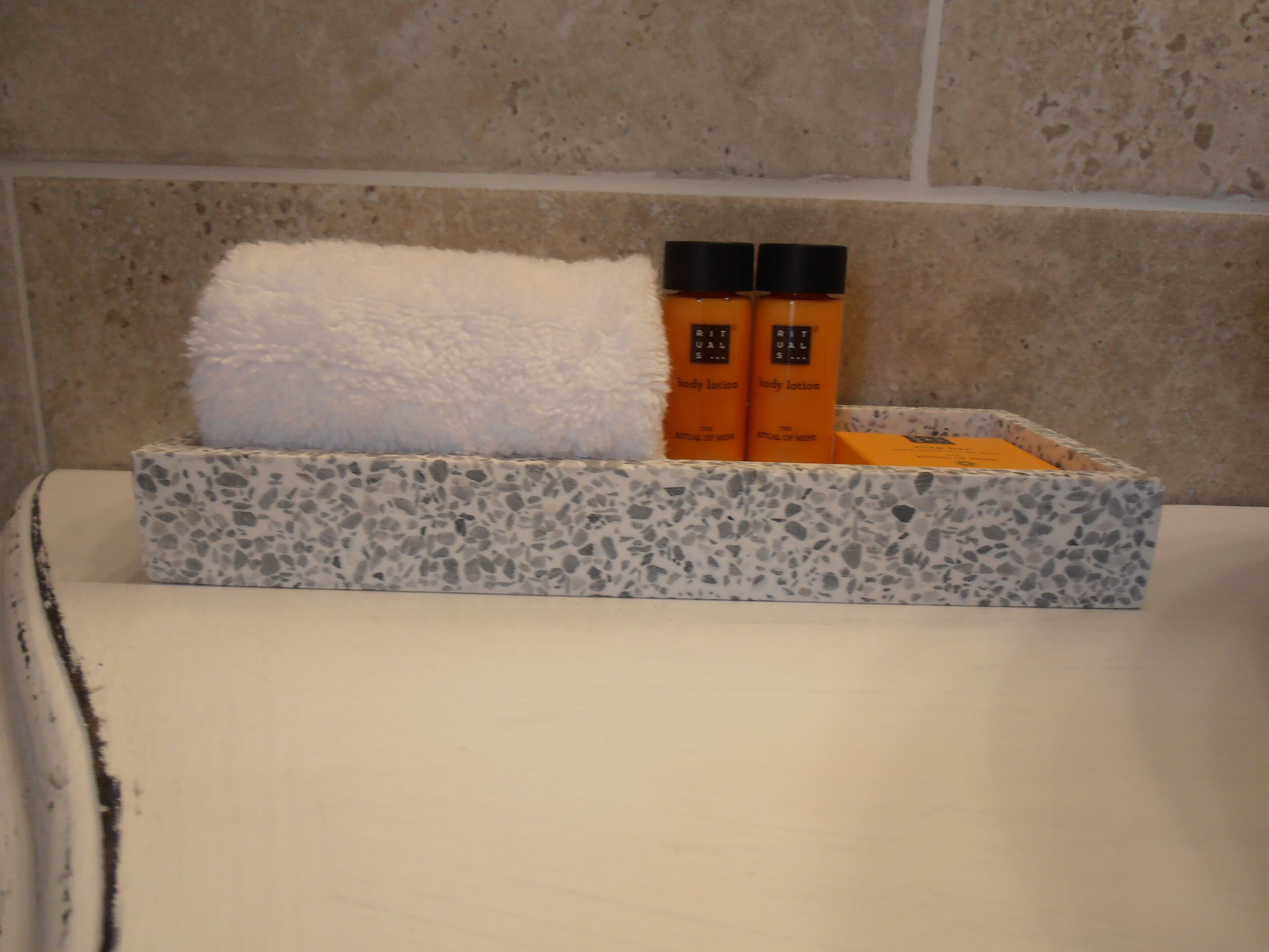 A bathroom with a marble sink, a white towel, and two bottles of body lotion.