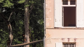 A two-story building with a stone facade, a wooden deck with outdoor furniture, and a garden with flowers. - MANOIR LE COUTUREAU (Rouffignac-de-Sigoulès)