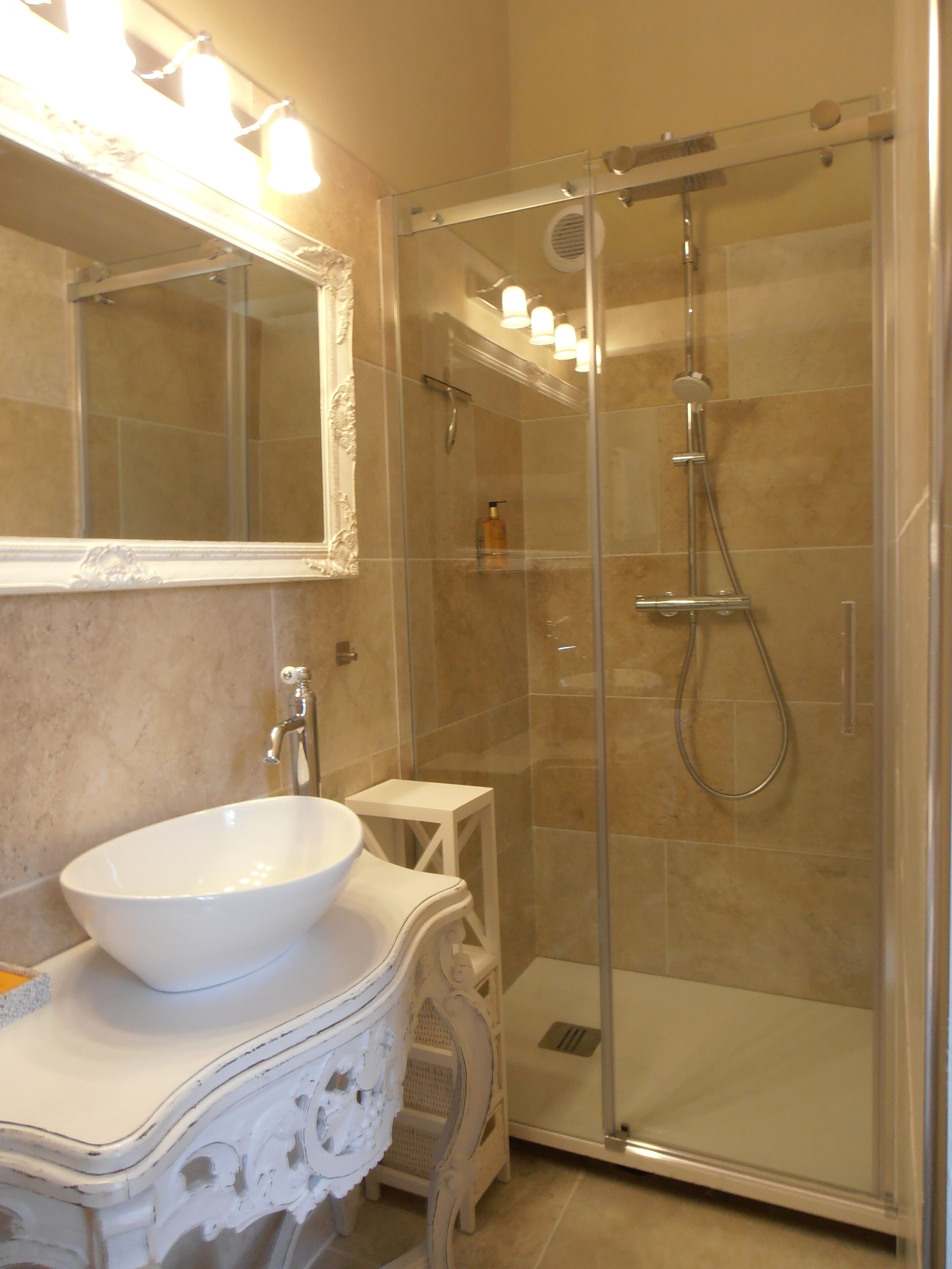 A bathroom with a white sink, a mirror, and a glass-enclosed shower.