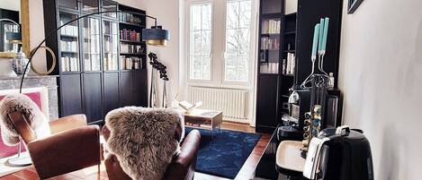 Una sala de estar moderna con piso de madera, un sillón cubierto de piel, una cafetera y una estantería.
