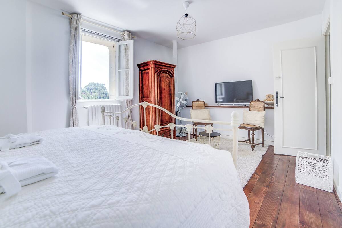 Una camera da letto con un letto grande, un'armadietto in legno, una televisione e un tavolino con sedie.