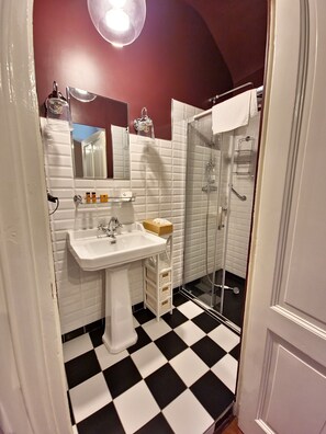A bathroom with a white sink, mirror, and a glass shower enclosure. - MANOIR LE COUTUREAU (Rouffignac-de-Sigoulès)