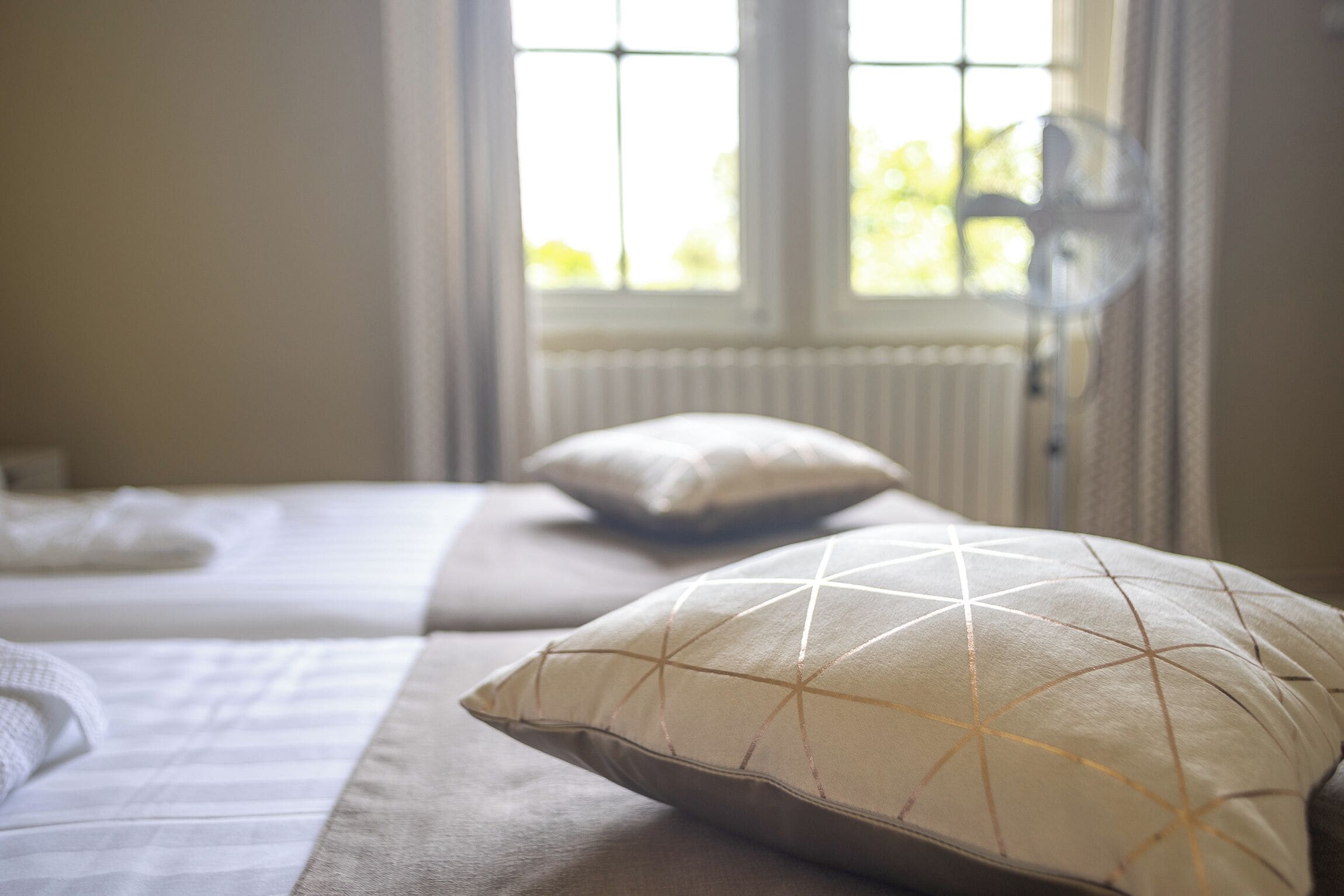 A bedroom with a bed, pillows, and a window with curtains.