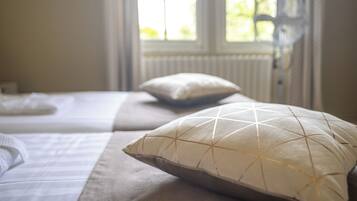 A bedroom with a bed, pillows, and a window with curtains.