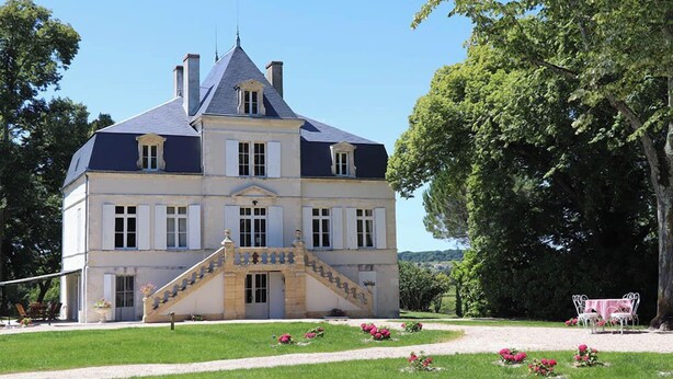 A large, historic building with a prominent staircase leading to the entrance, surrounded by lush greenery and a well-maintained lawn. - MANOIR LE COUTUREAU (Rouffignac-de-Sigoulès)