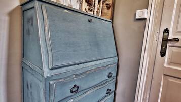 A blue dresser with three drawers, a small basket, and a framed picture on top.