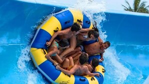 A group of people on a blue and yellow inflatable raft in a water slide.
