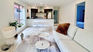 A modern living room with a sofa, coffee table, and dining area.