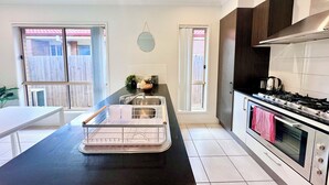 A modern kitchen with a black countertop, stainless steel appliances, and a window with a view of a wooden fence.